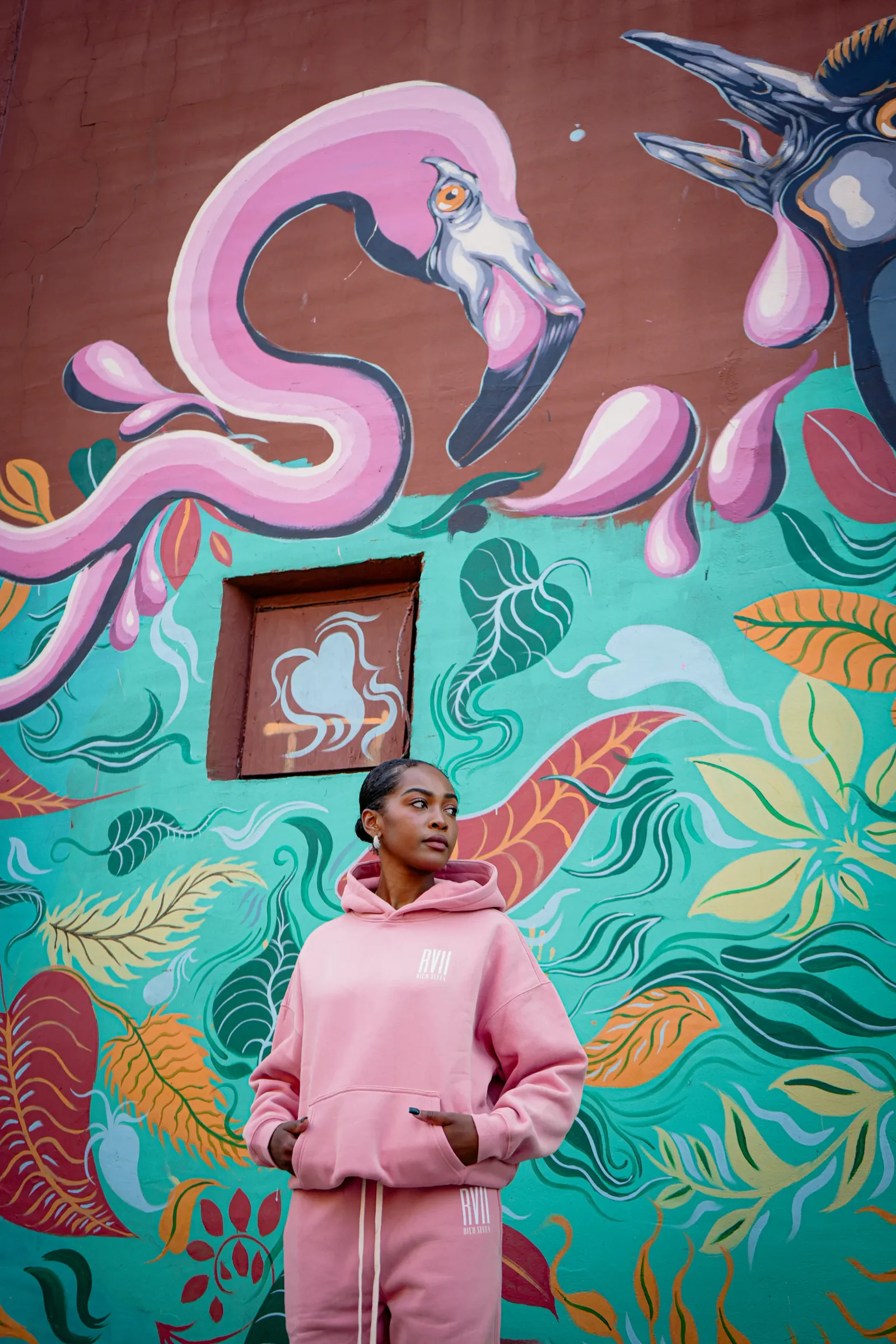 A person in a pink outfit standing in front of a colourful mural