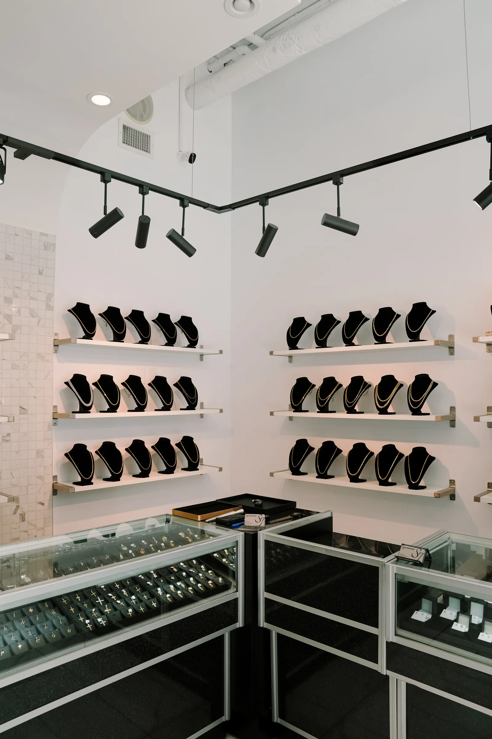 Gold chains displayed on black busts inside a bright jewellery store